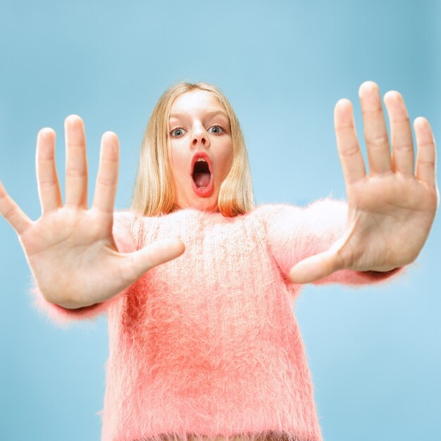 Reject, rejection, doubt concept. Young emotional teen girl at studio rejecting something against blue background.