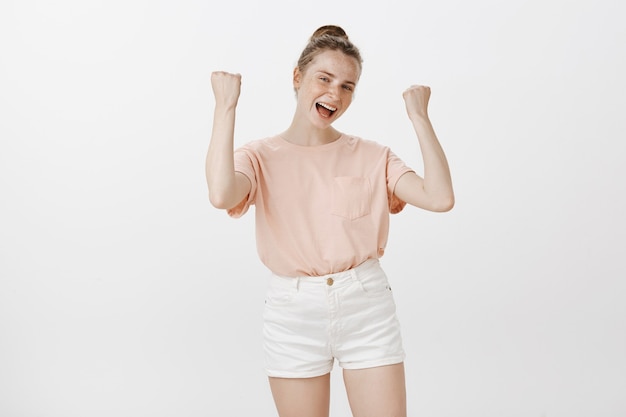 Rejoicing cheerful teenage girl posing against the white wall