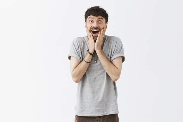 Rejoicing happy handsome guy posing against the white wall