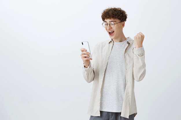 Rejoicing teenage guy posing against the white wall