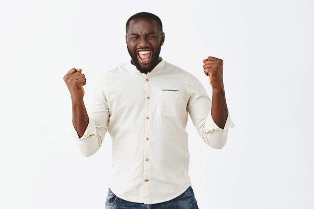 Rejoicing young guy posing against the white wall