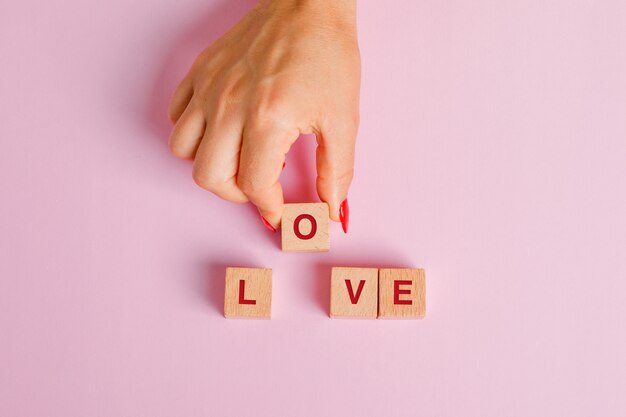 Relationship concept flat lay. female pulling out wooden letter cube.