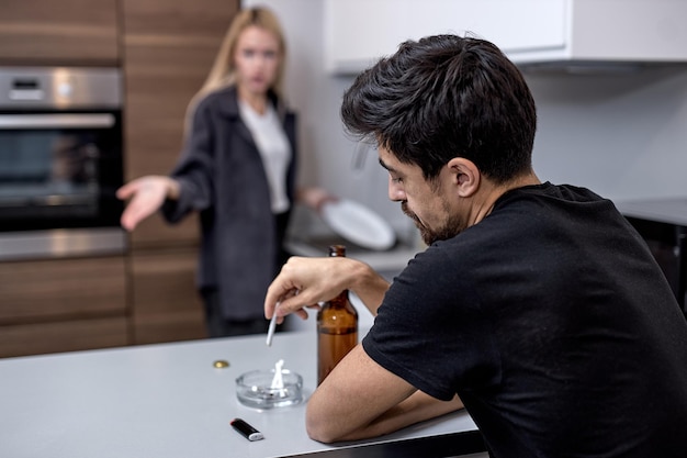 Relationship problem. portrait of american couple arguing  angry displeased woman screaming at calm smoking husband who ignoring her  tired of enduring a tantrum from wife. in kitchen at home