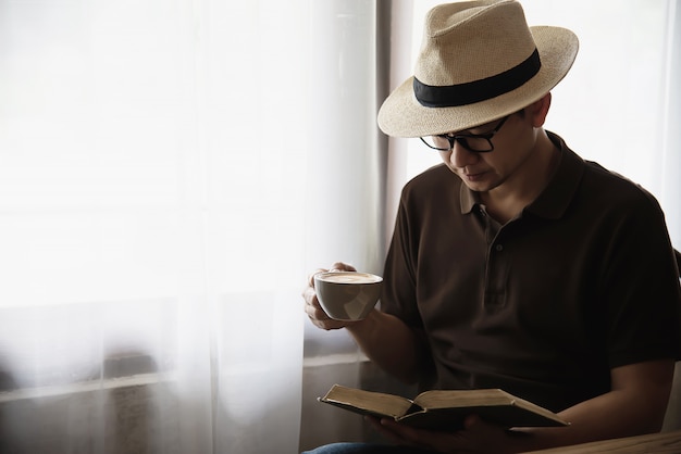 Relax Asian man drinking a coffee and reading a book