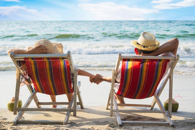 リラックスしたカップルは海の波とビーチチアに横たわって - 男と女は海の自然の概念で休暇を過ごす