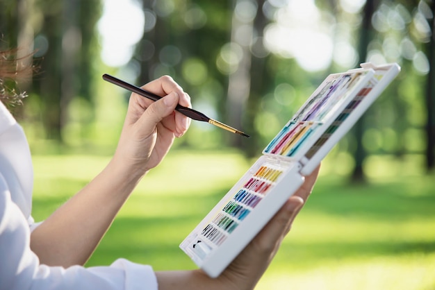 Relax woman painting watercolor art work in green garden forest nature 