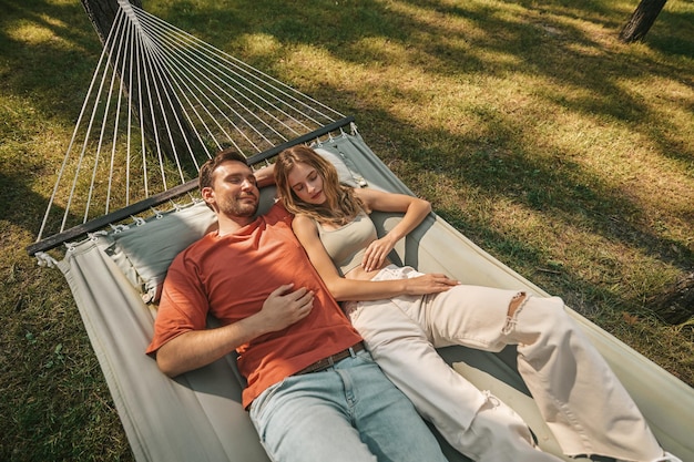 Relaxation. A man and a woman lying in a hammock and feeling relaxed