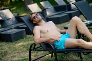 Free photo relaxation. young man lying in a chaise longue and looking relaxed