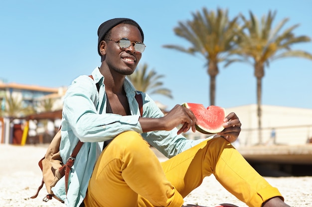 Free photo relaxed adventurer eating fresh ripe watermelon