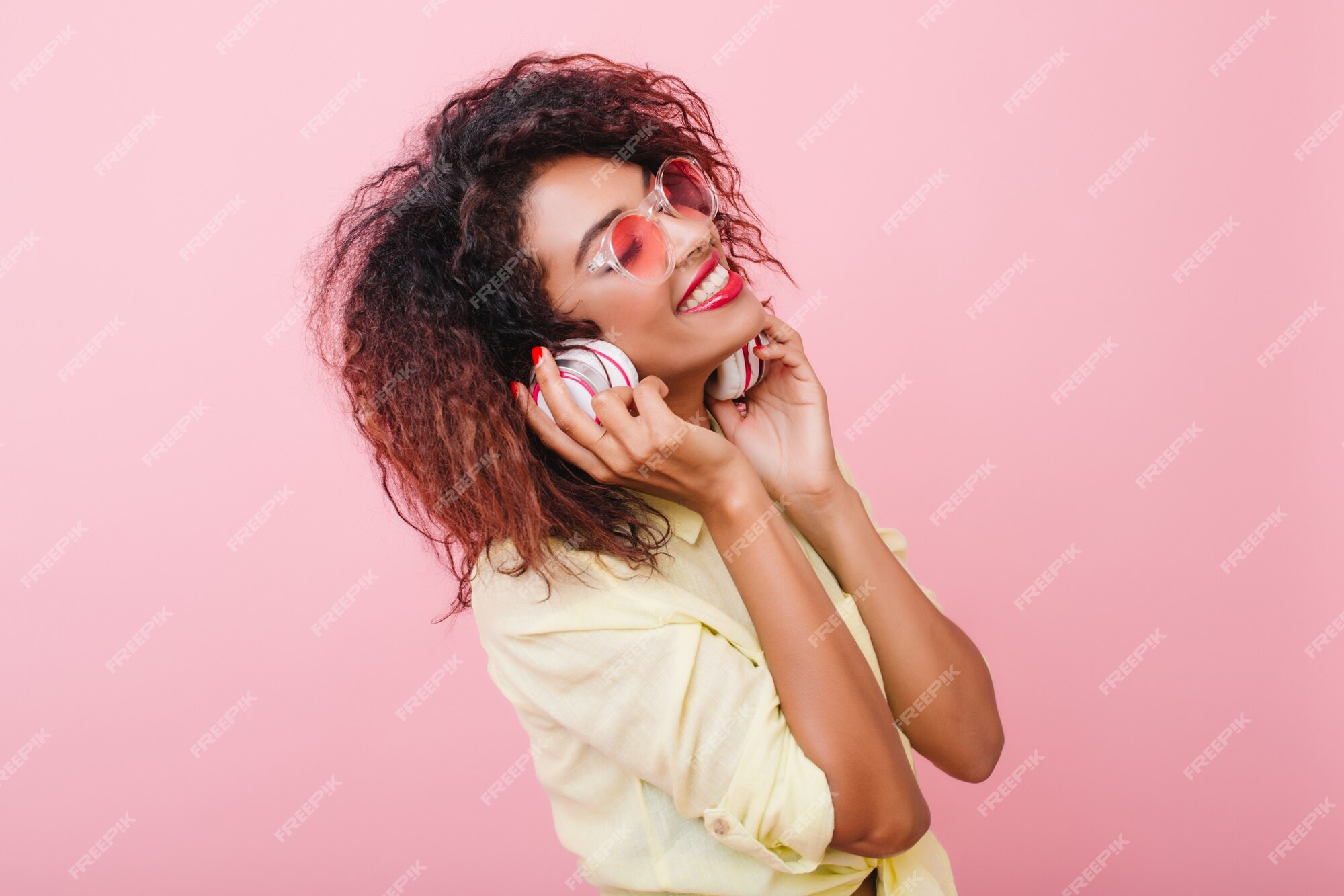 Free Photo | Relaxed african woman with light-brown skin listening music  with eyes closed and happy face expression. trendy curly black girl in  yellow cotton shirt holding earphones and smiling