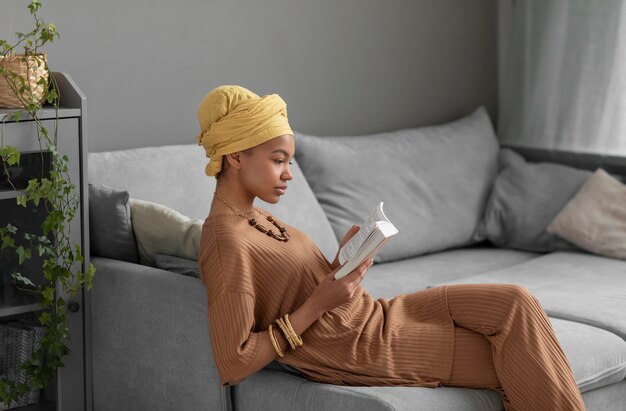 Расслабленная арабская женщина, читающая книгу дома