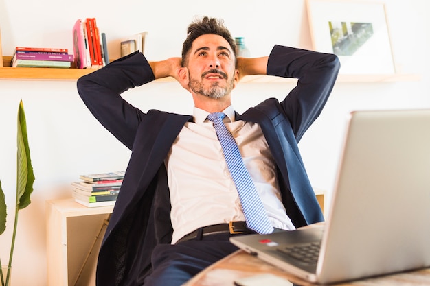 Relaxed businessman looking up with his mobile phone on table