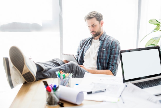 Free photo relaxed businessman with notepad sitting in office