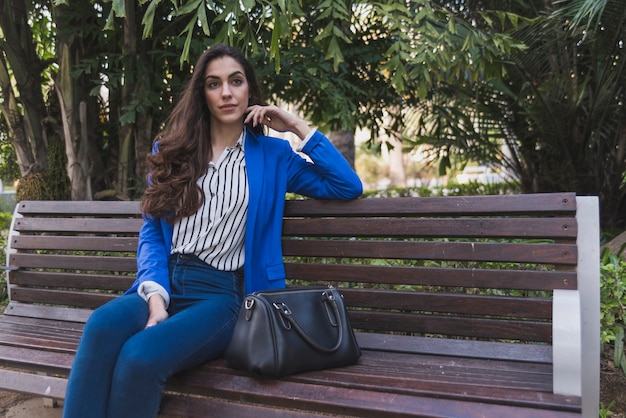 Free photo relaxed businesswoman sitting on a park bench