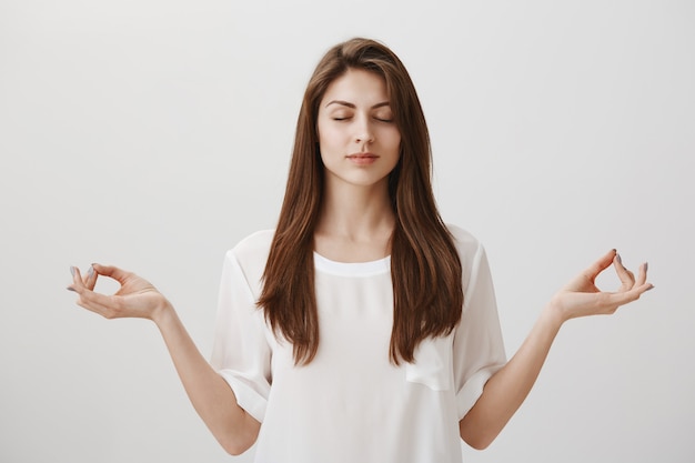 Relaxed and calm young woman meditating with hands spread sideways