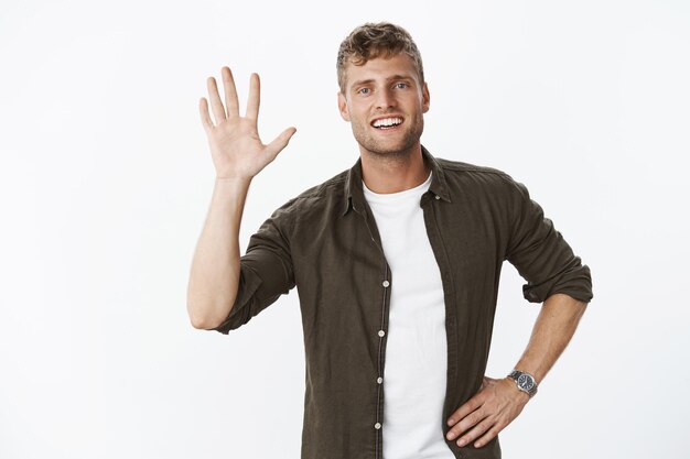 Relaxed and carefree friendly young masculine sportsman raising palm as giving high five or saying hello