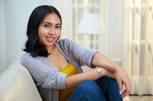 Расслабленная филиппинская женщина сидит на диване