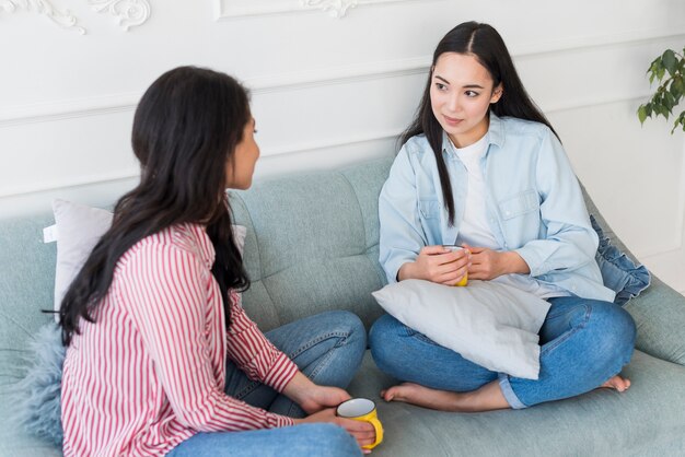 Relaxed friends talking while sitting on couch