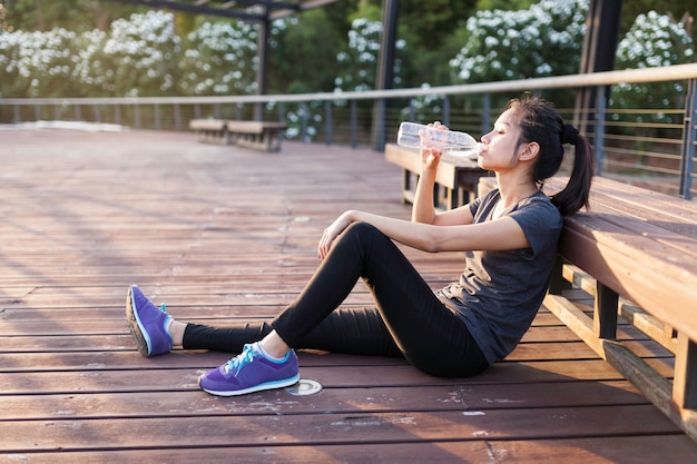 Relaxed girl drinking water after training