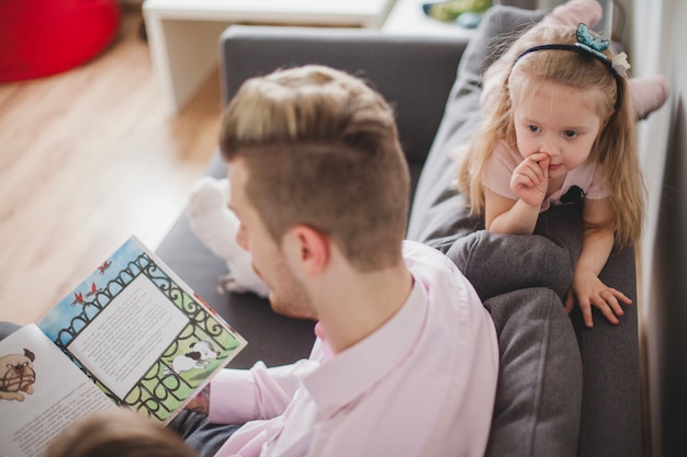 Relaxed girl listening to her father reading a story