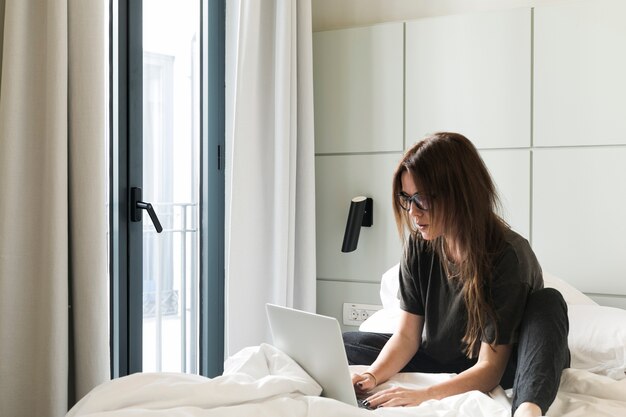 Расслабленная девушка с ноутбуком на кровати