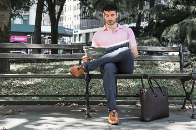 Relaxed man reading newspaper on street