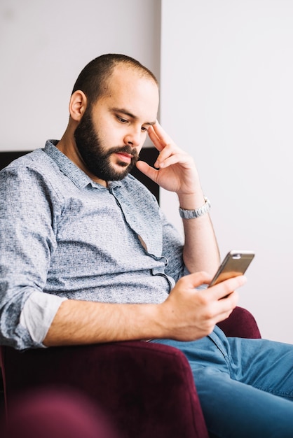 Relaxed man with smartphone in chair