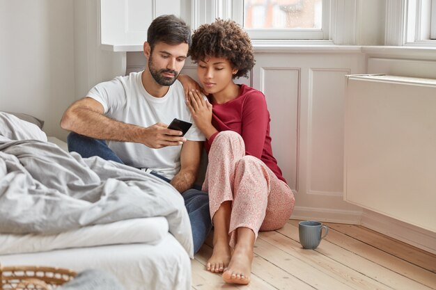 Relaxed multiethnic boyfriend and girlfriend sit on floor at home