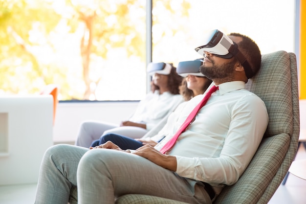 Relaxed multiethnic business colleagues in VR headsets