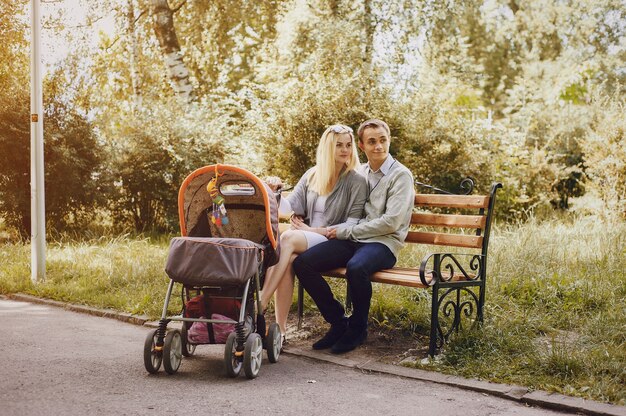 Ослабленный родители с коляской, сидя на скамейке в парке