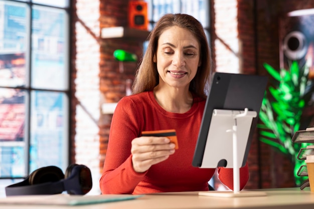 Relaxed person holds her card while she pays online for her order