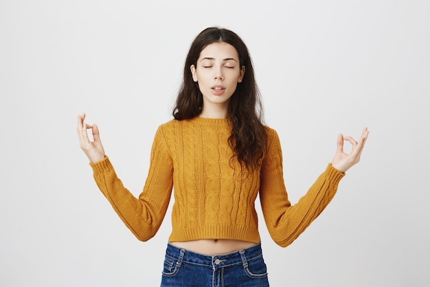 Free photo relaxed pretty girl close eyes and meditating, calm down