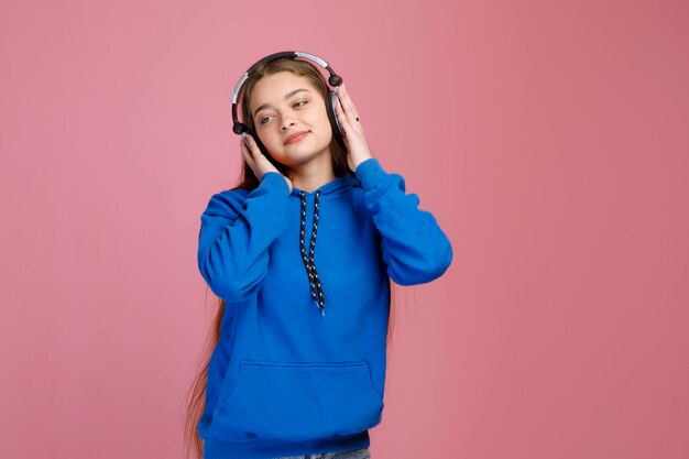 Relaxed pritty girl pressing headphones to ear while listening to music inside