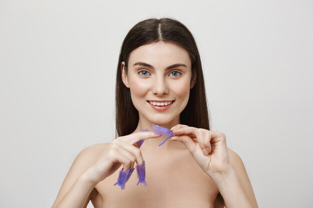 Relaxed smiling woman standing naked painting nails