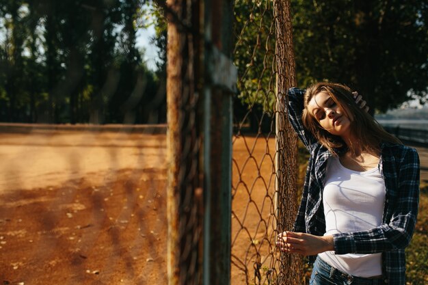 Relaxed teenager next to a fence