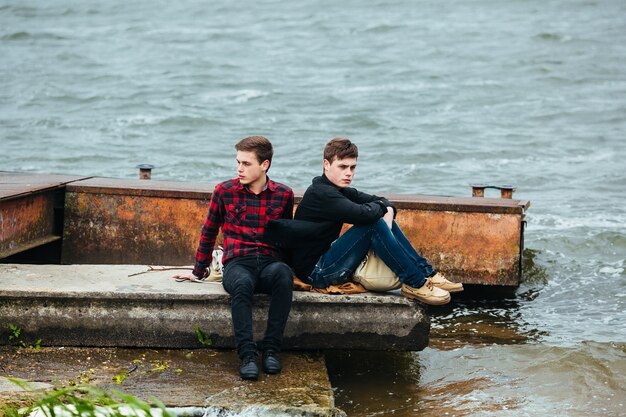 Relaxed teenagers sitting on the old pier