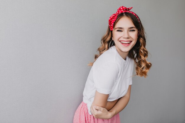 Relaxed white girl with red ribbon enjoying and smiling. inspired caucasian lady with wavy hairstyle.