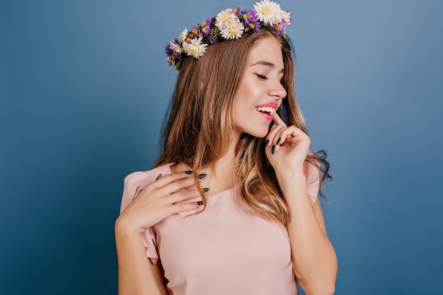 Relaxed white woman in circlet of flowers posing with eyes closed
