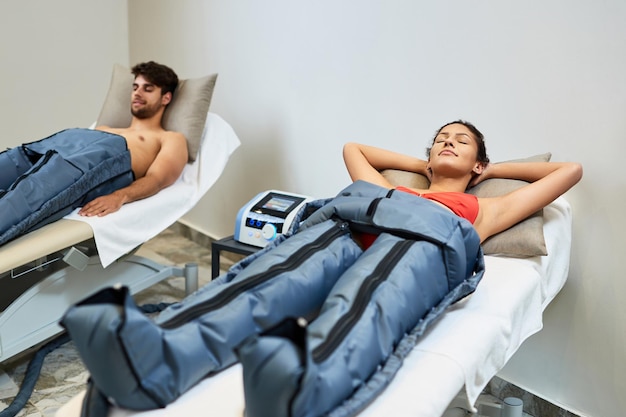 Free photo relaxed woman and her boyfriend enjoying in pressotherapy at wellness center