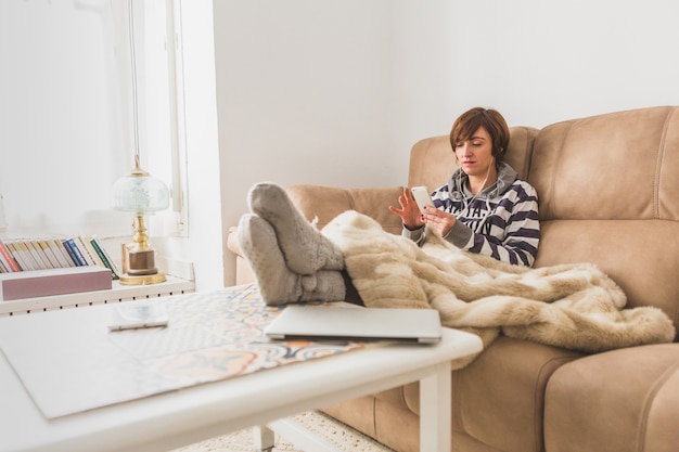 Foto gratuita relaxed donna utilizzando il suo telefono cellulare a casa