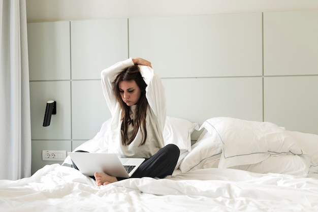 Free photo relaxed woman watching laptop on bed