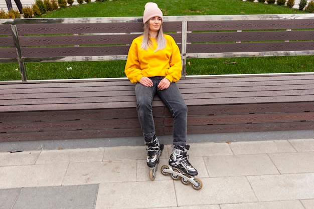 Relaxed woman wearing roller blades sitting on bench