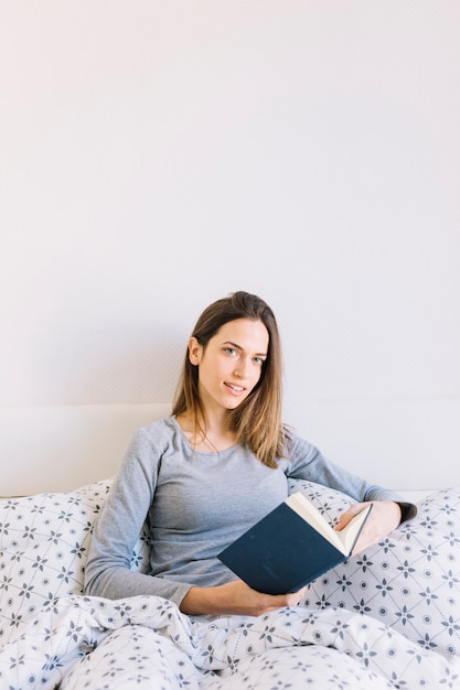 Relaxed woman with book looking at camera
