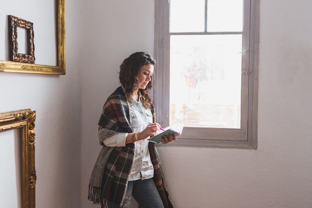 Relaxed woman writing next to the window