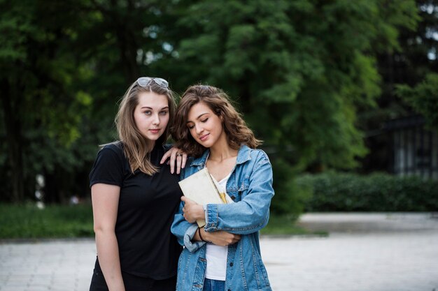 Relaxed young females standing on park sidewalk