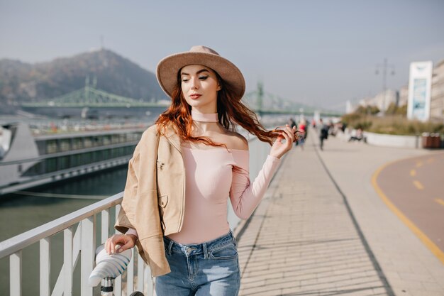 Relaxed young woman plays with red hair on mountains