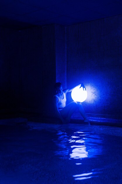 Relaxed young woman in pool with neon light