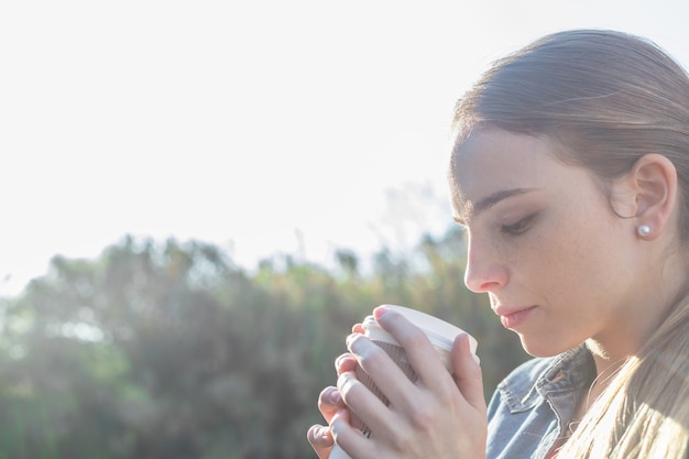 ホットドリンクを飲みながらリラックスした若い女性