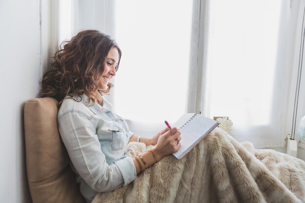 彼女のノートブックに書いてリラックス若い女性