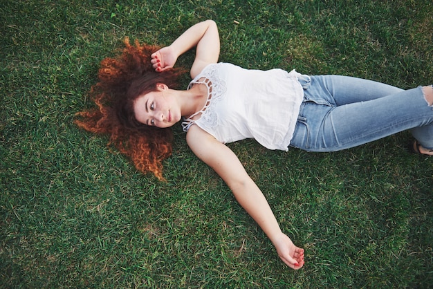 Relaxing girl with red, lying on the grass.